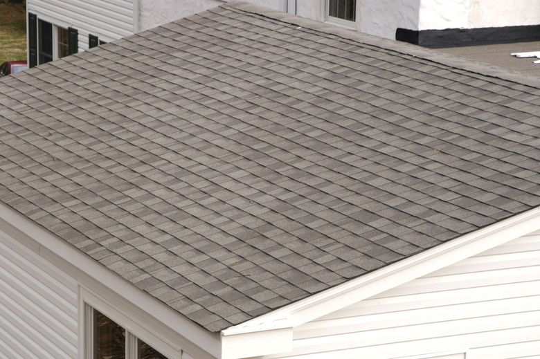 Grey asphalt shingle roof on a white building, angled view.