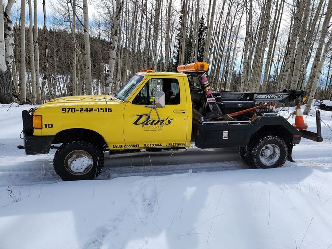 Tow truck towing a gray SUV on a city street.