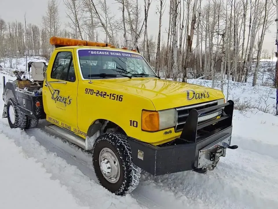 Yellow tow truck in snow, with Craig's name and phone number.