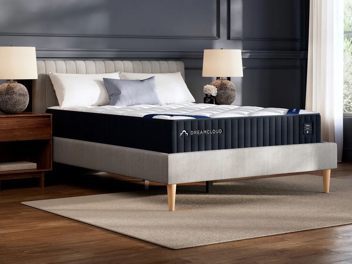 Dark blue mattress on a light gray bed frame in a bedroom with nightstands and lamps.