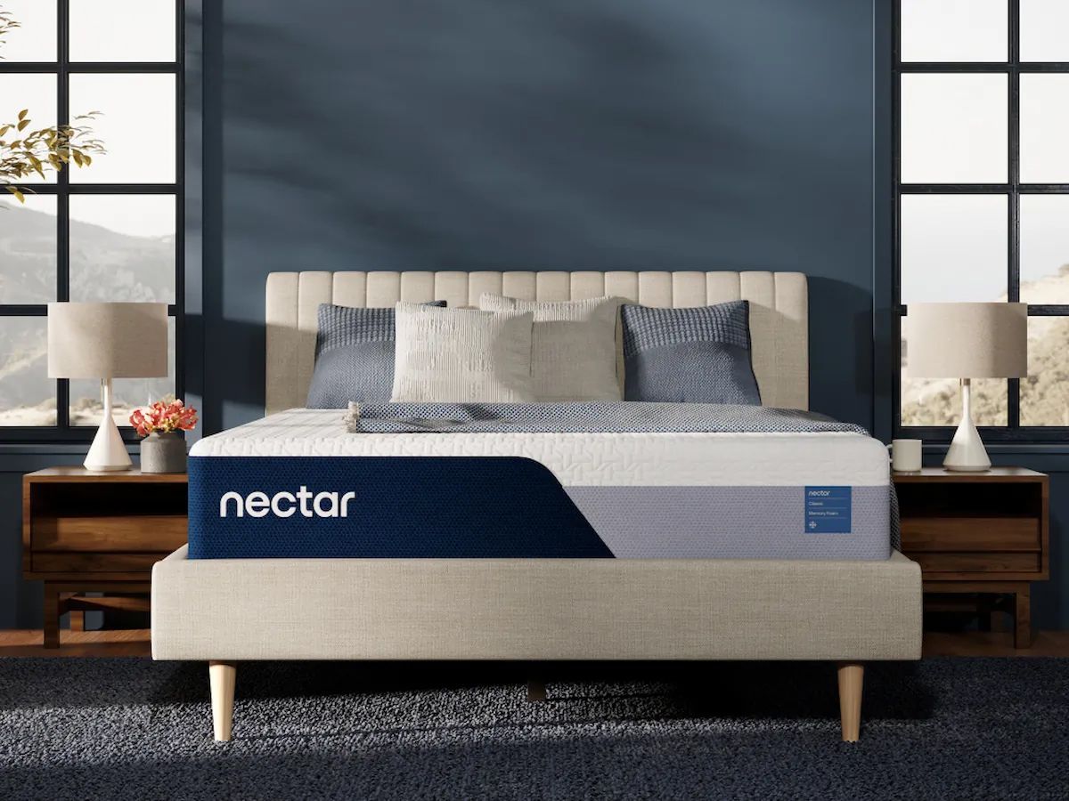 Nectar mattress on a bed in a bedroom; dark blue wall, two nightstands with lamps, pillows, and a rug.