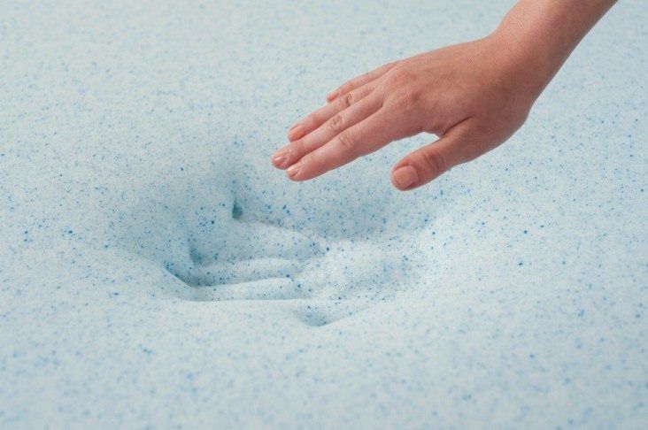 Hand pressing into light blue memory foam, leaving an imprint.
