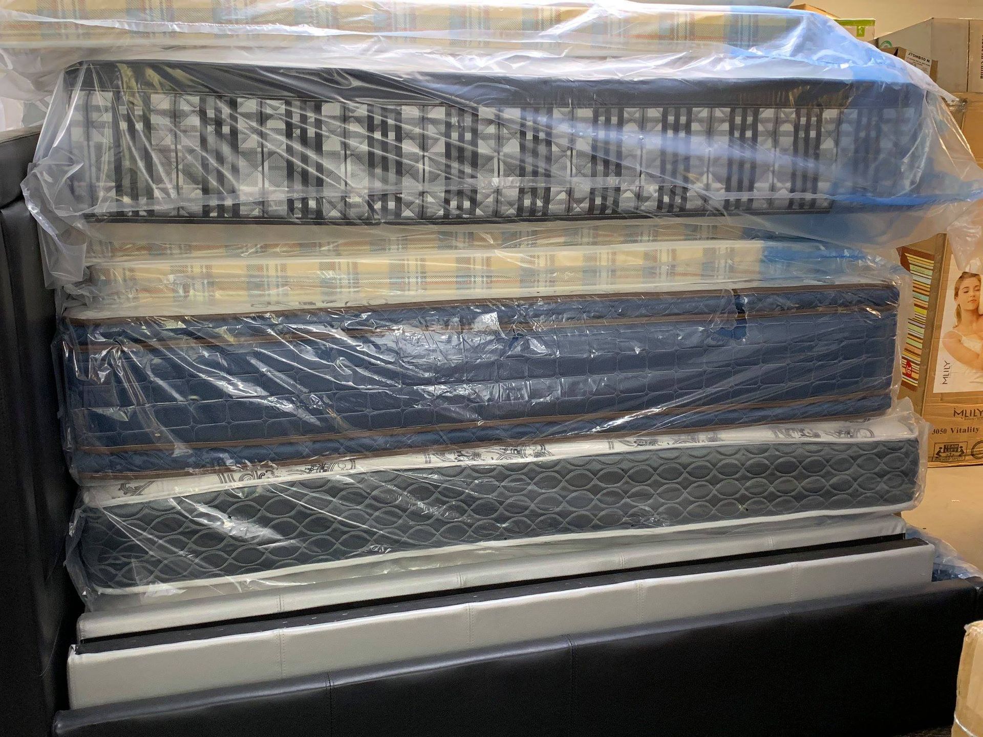 Stacked, plastic-wrapped mattresses in a black container.