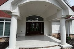 A large porch with columns and steps leading to the front door of a house.