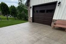 A concrete driveway leading to a garage with a bench in front of it.