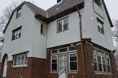 A large brick house with a white siding and a brown roof.