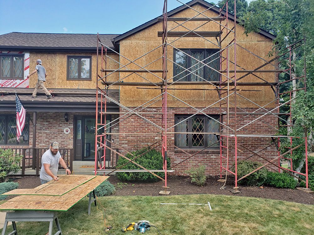 A man is standing in front of a house with scaffolding around it.