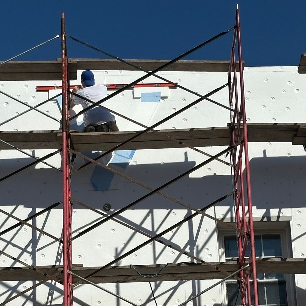 A man is standing on a scaffolding on the side of a building