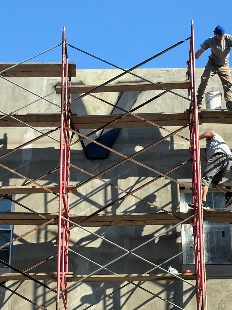 Two men are working on a building on scaffolding