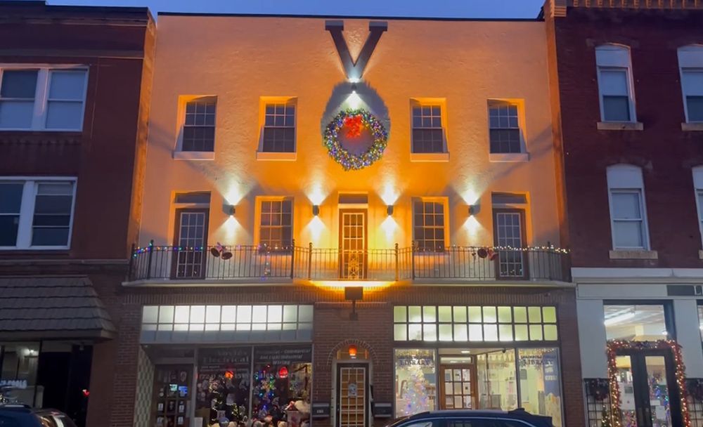 A building with a wreath on the front of it is lit up at night.