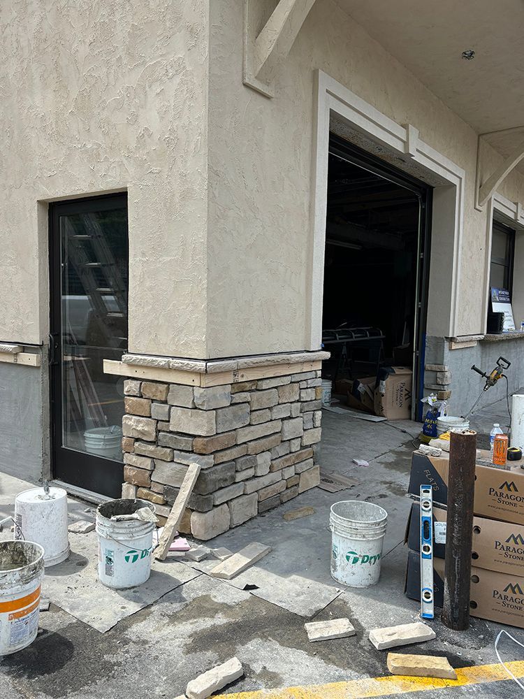 A building is being remodeled with stone siding and a black door.