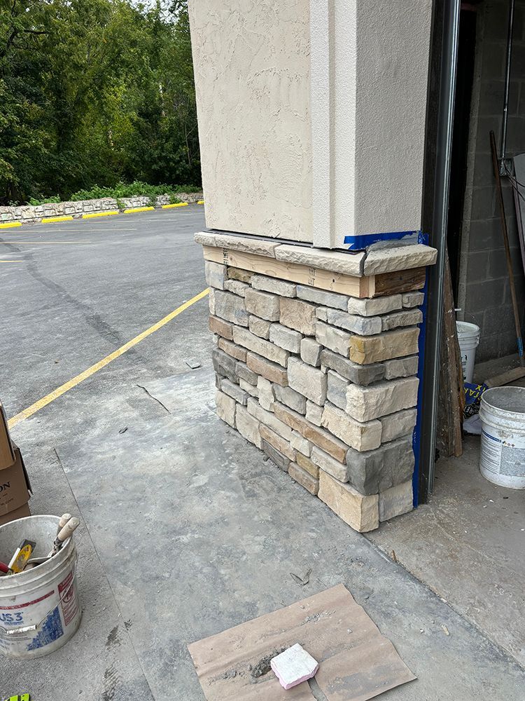 A stone wall is being built on the side of a building.