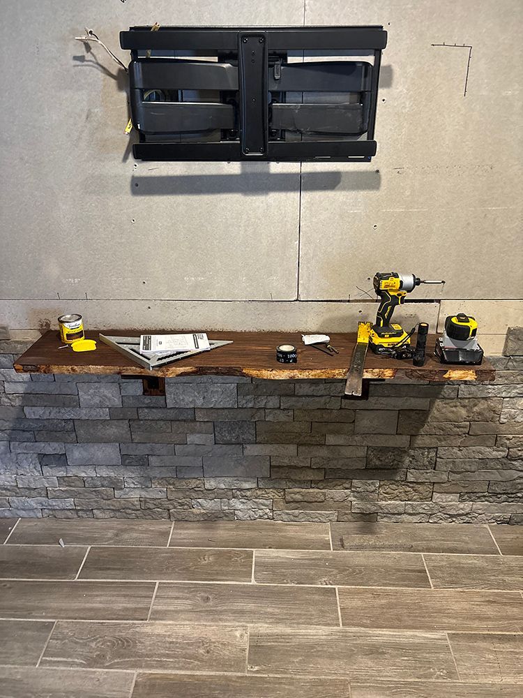 A wooden shelf with a drill and other tools on it.