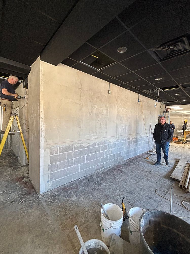 A man is standing on a ladder in a room under construction.