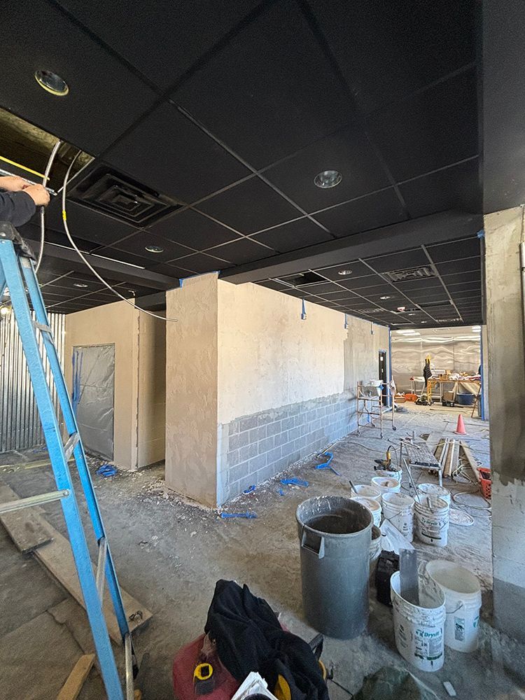 A man is standing on a ladder in a building under construction.