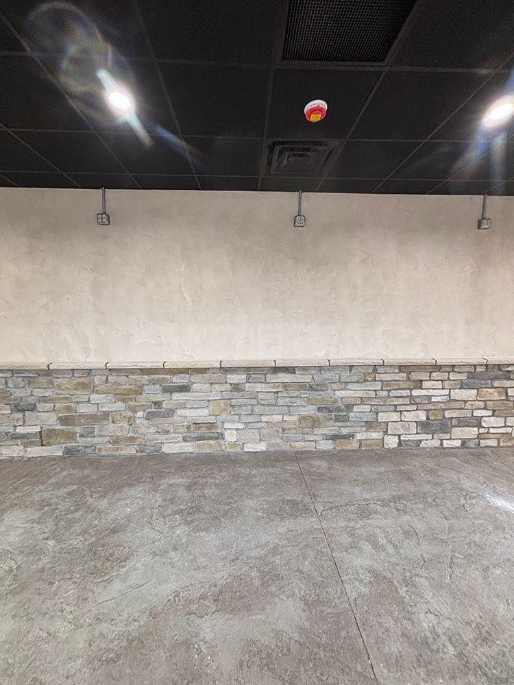 An empty room with a stone wall and a black ceiling.