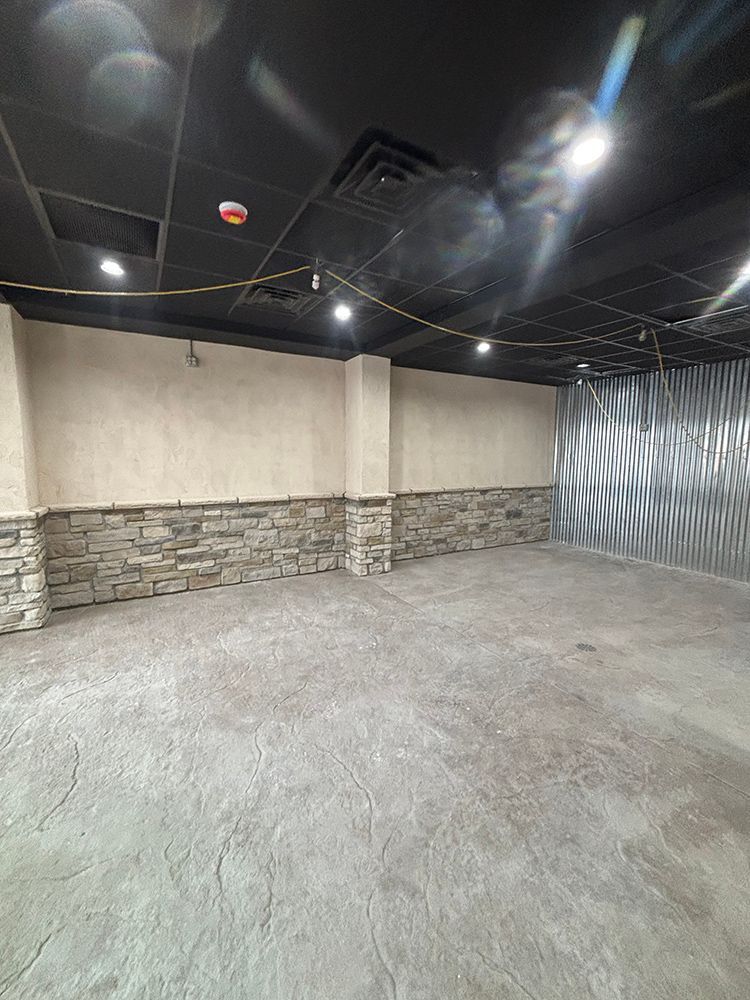 An empty room with a stone wall and a black ceiling.