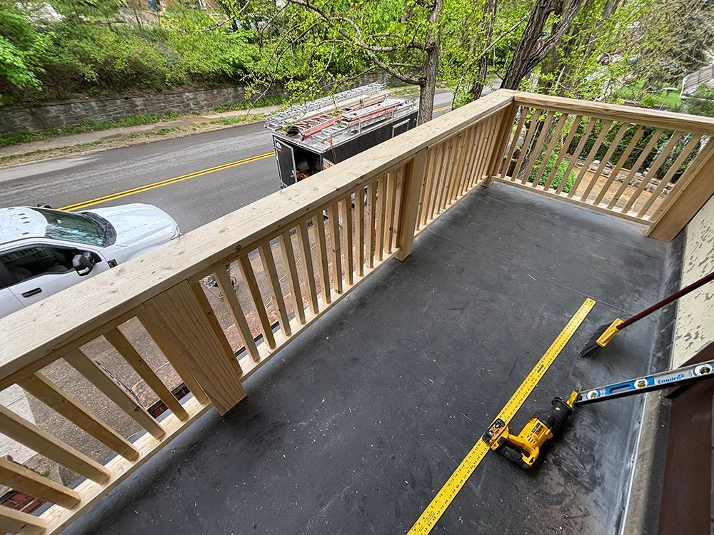A car is parked on the side of the road next to a balcony.