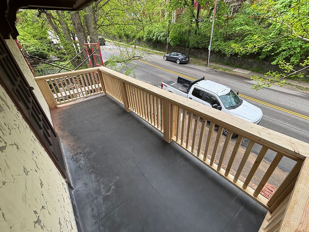 A white truck is parked on the side of the road on a balcony.
