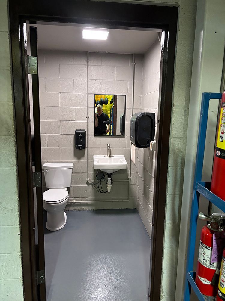 A bathroom with a toilet , sink and mirror.