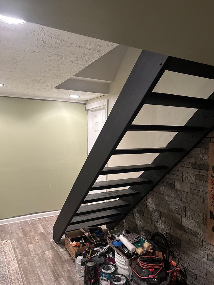 A staircase in a basement with a lot of tools on the floor.