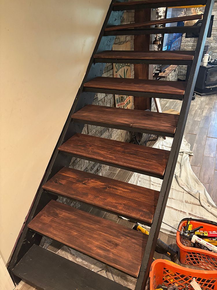 A wooden staircase with a metal frame is being painted in a room.