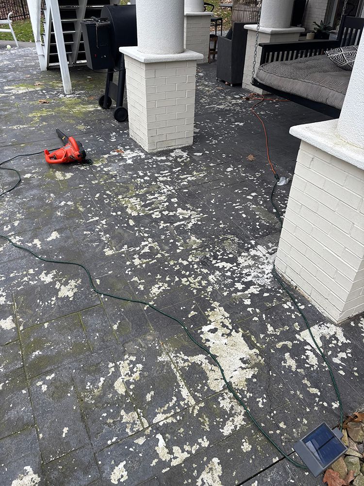 A patio with a lot of stains on it and a drill on the ground.