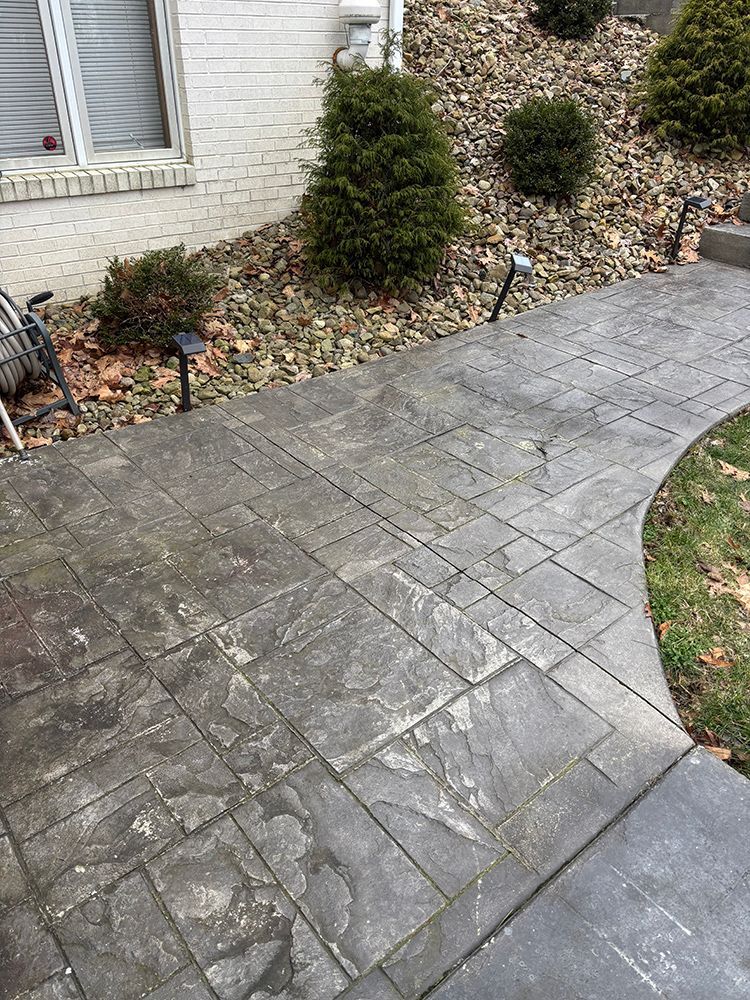 A concrete walkway leading to a house with lights on it.