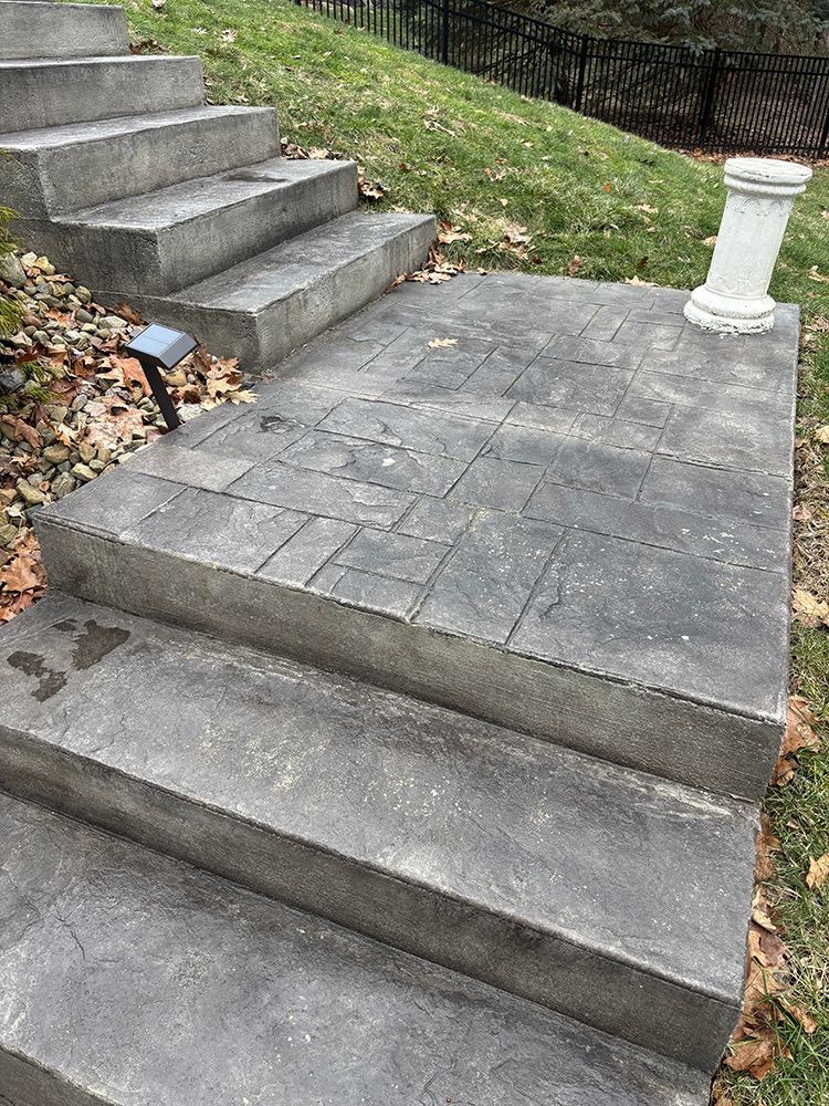 A set of concrete stairs leading up to a grassy hill.