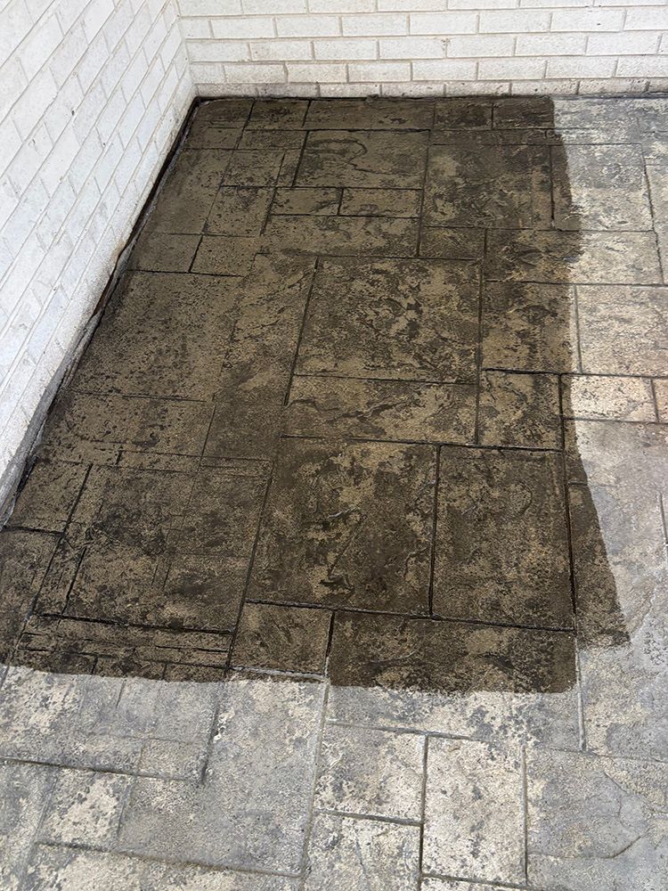 A concrete floor with a brick wall in the background.