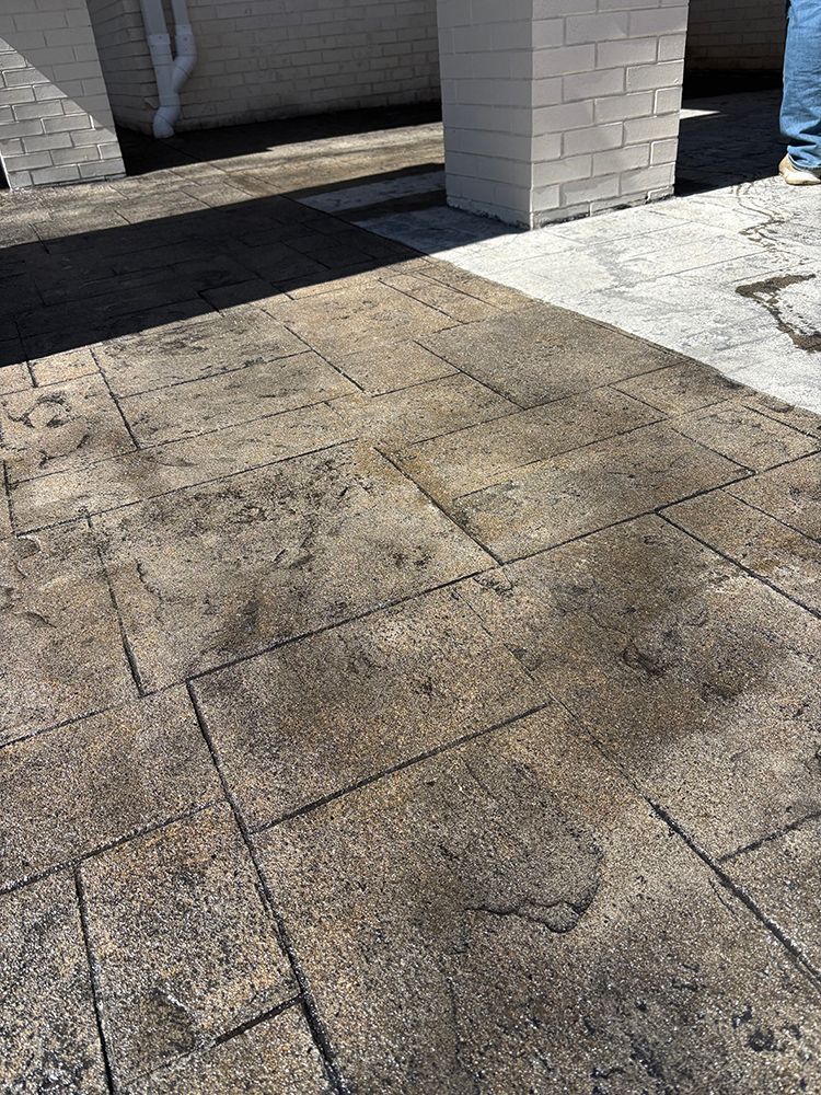 A dirty concrete floor with a brick wall in the background.