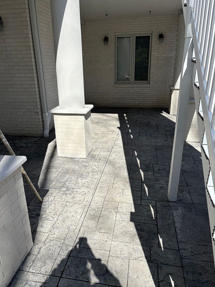 A shadow of a person is cast on a concrete walkway in front of a white building.