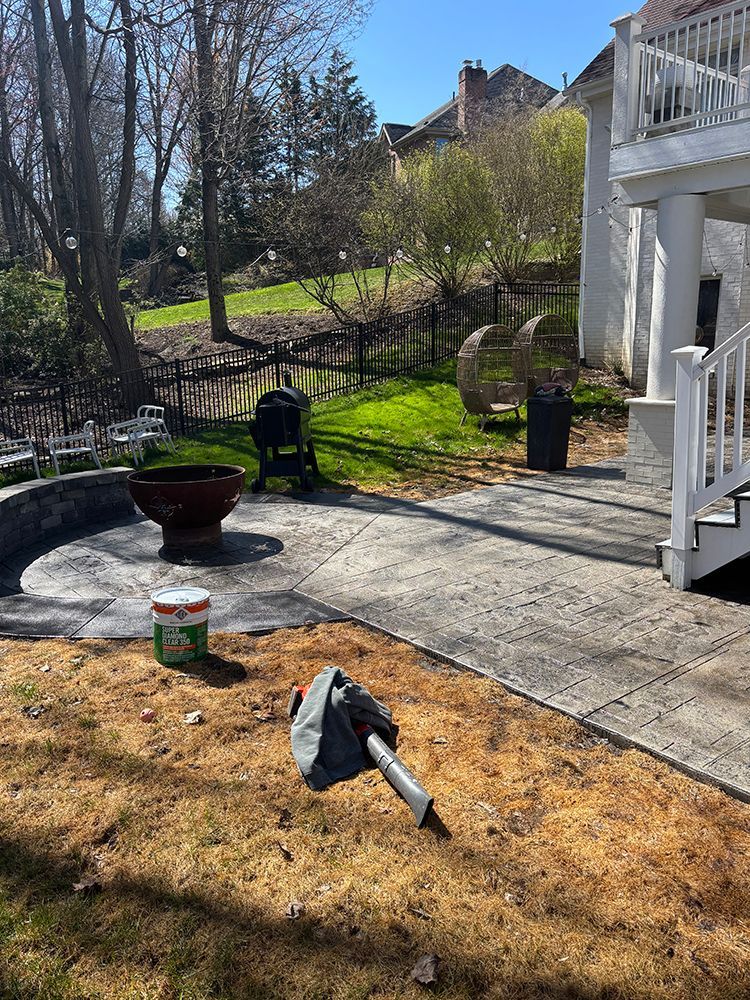A patio with a chair and a bucket of dirt in front of a house.