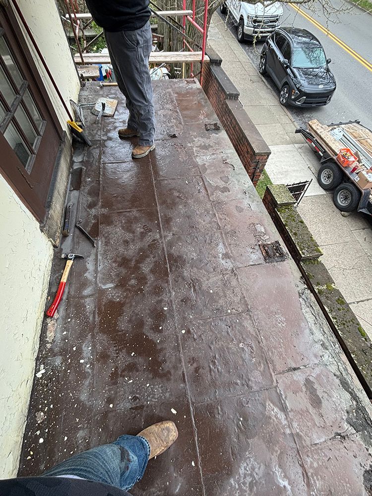 A man is standing on a balcony with a broom.