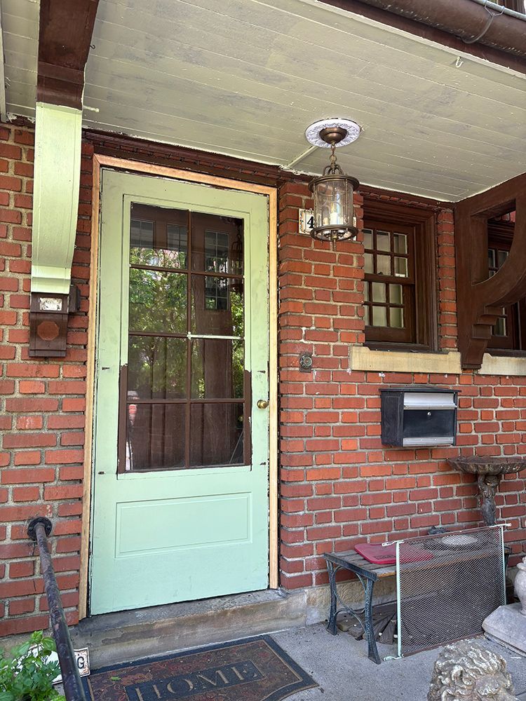 A brick house with a green door and a mailbox