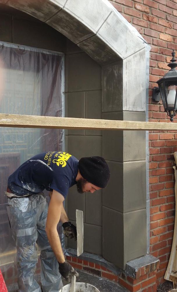 A man is working on a brick wall with a trowel.