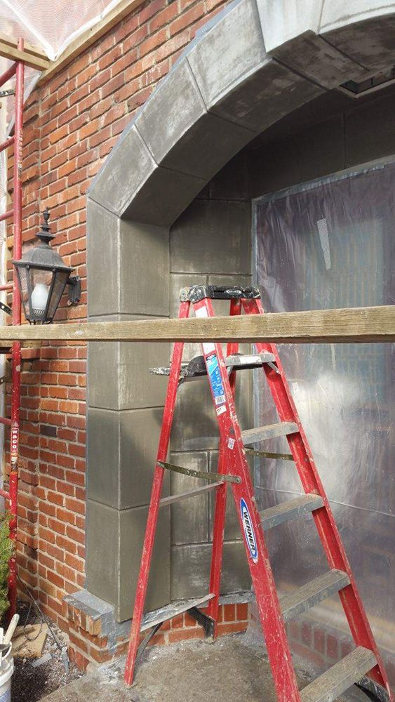 A red ladder is sitting on top of a wooden scaffolding next to a brick wall.