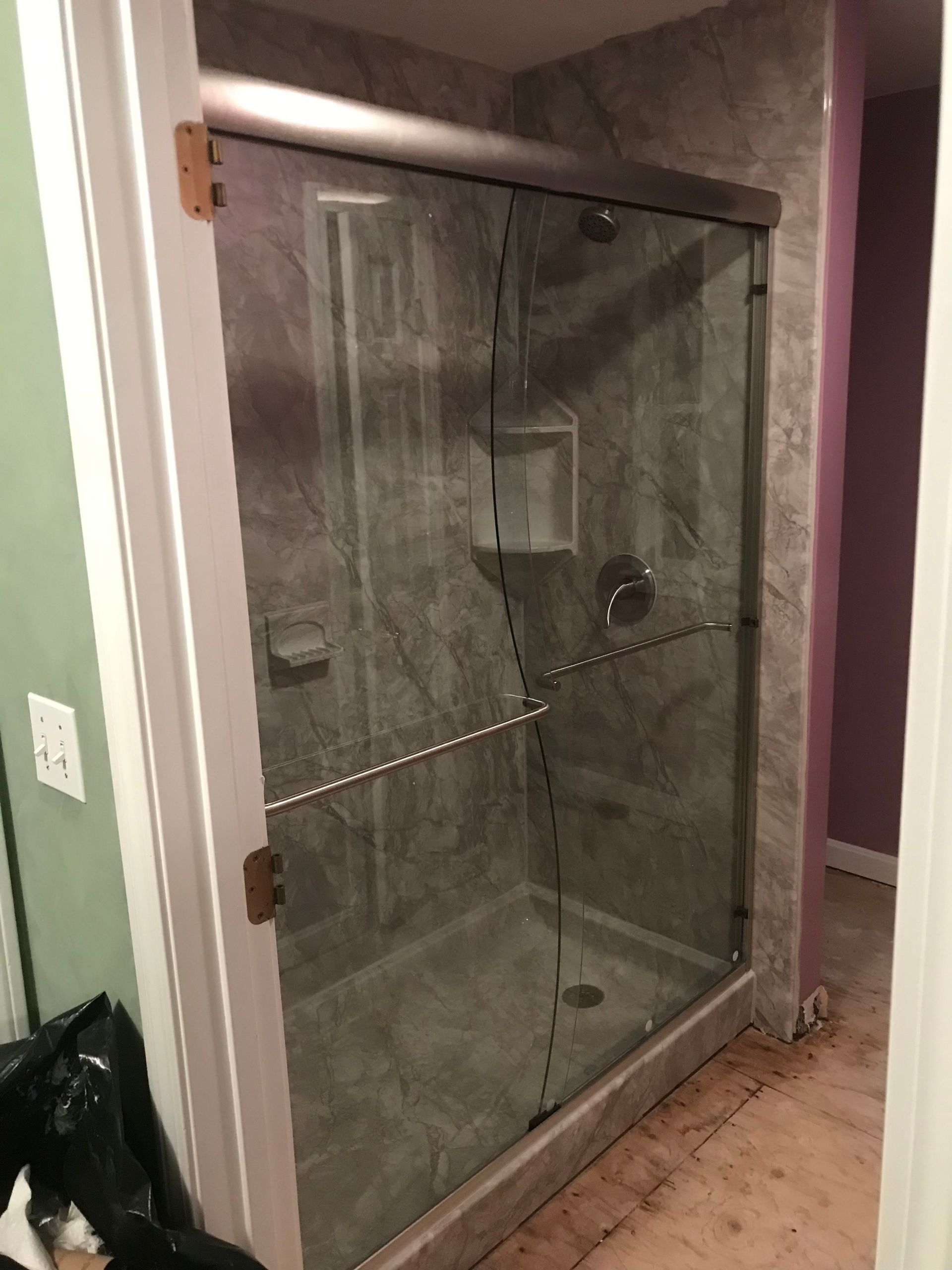 Glass shower enclosure with gray tiled walls and floor.