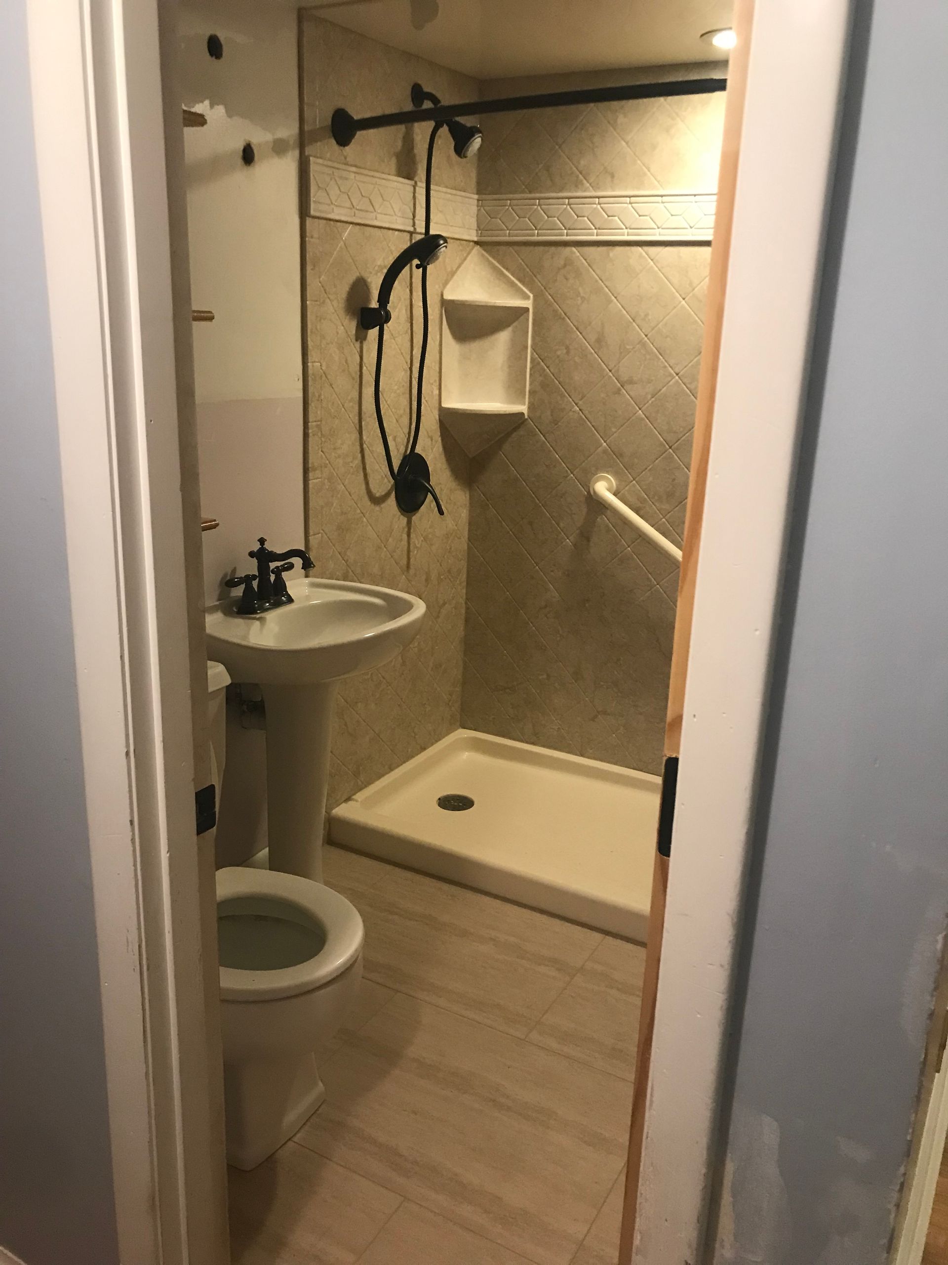 Small bathroom with a toilet, pedestal sink, and shower stall with a grab bar.