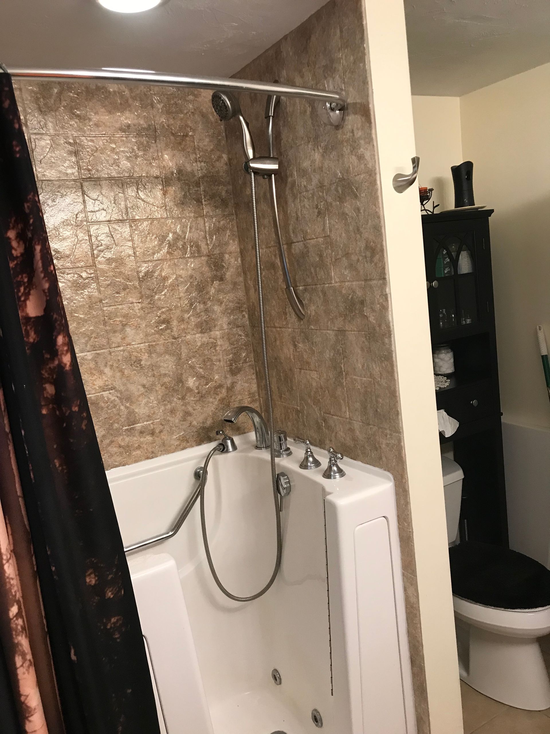 White walk-in tub shower with brown tile wall and curtain in bathroom.
