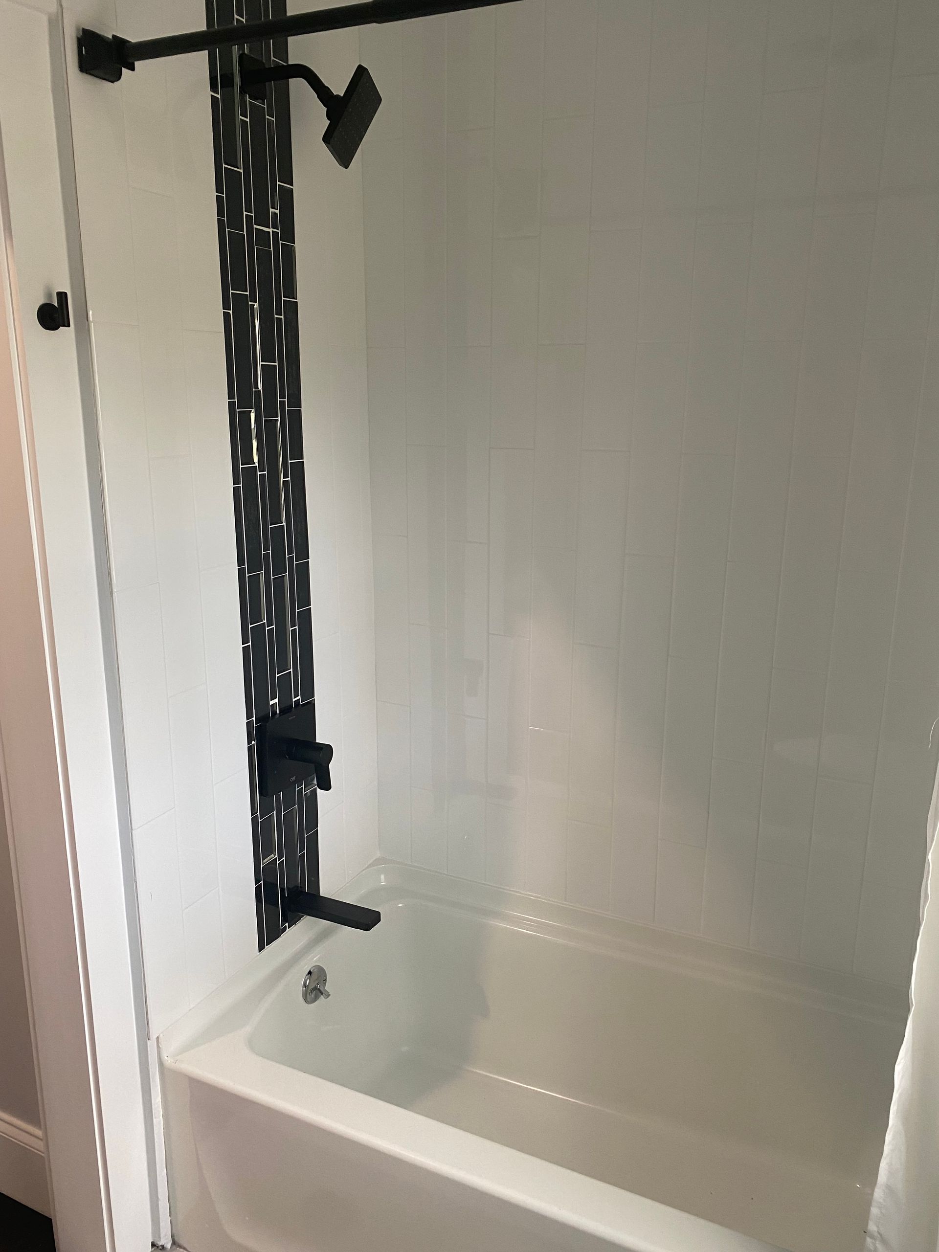 White bathroom with black shower fixtures, including a showerhead and tub faucet.