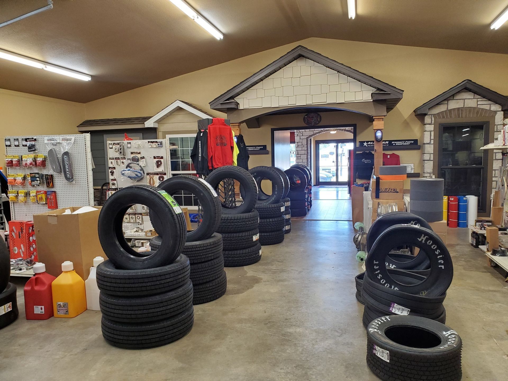 Interior of a shop with tires stacked in rows. Shop entrance is visible in the background.