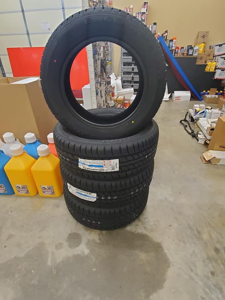 Four new black tires stacked on top of each other. One tire rests on top.