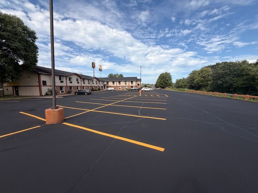 Empty parking lot with yellow lines beside a two-story building under a partly cloudy sky