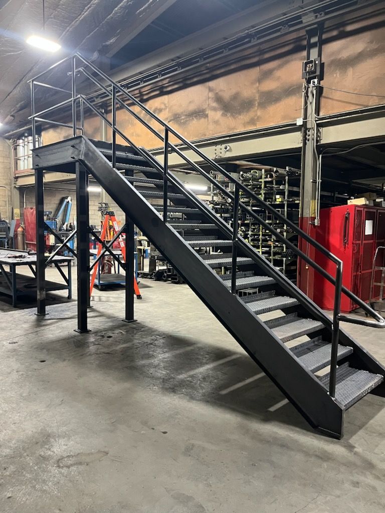 Black metal staircase leading up to a platform in an industrial setting.