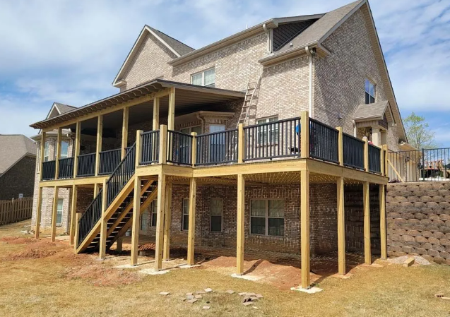 Two-story house with a wooden deck and screened-in porch, black railings, and brick exterior.