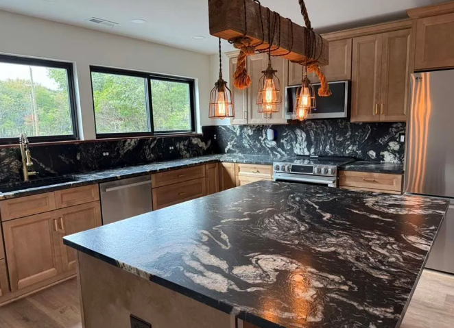 Kitchen with black and white countertops, wooden cabinets, and decorative hanging lights.