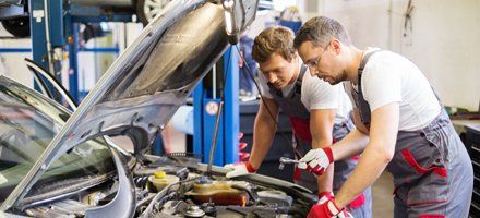 Two auto repairmen checking the car engine