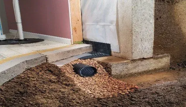 A hole in the ground next to a wall in a basement