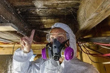 A man wearing a gas mask and goggles is looking under a wooden ceiling